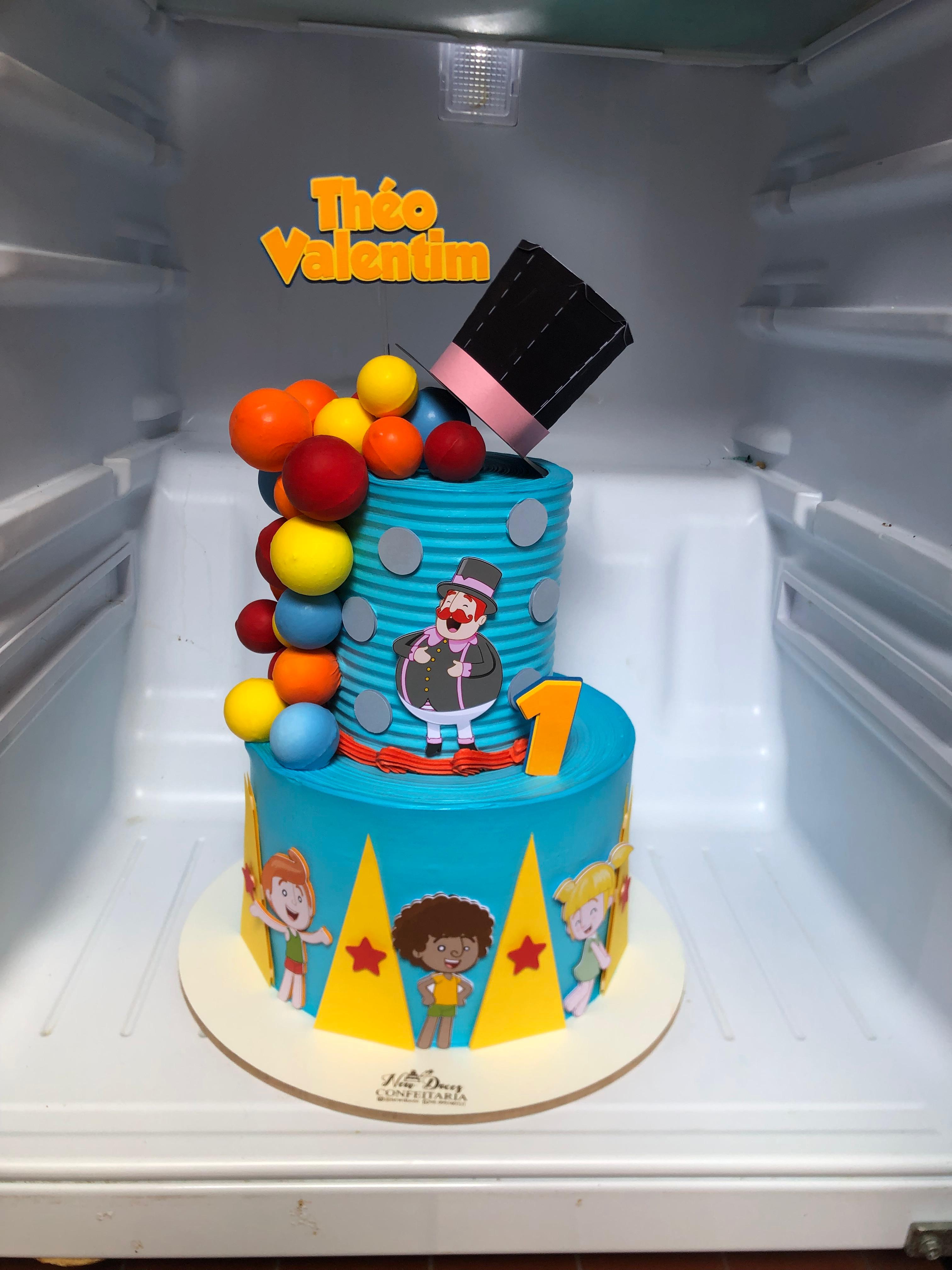 Bolo de dois andares com decoração colorida de circo, cartola e balões