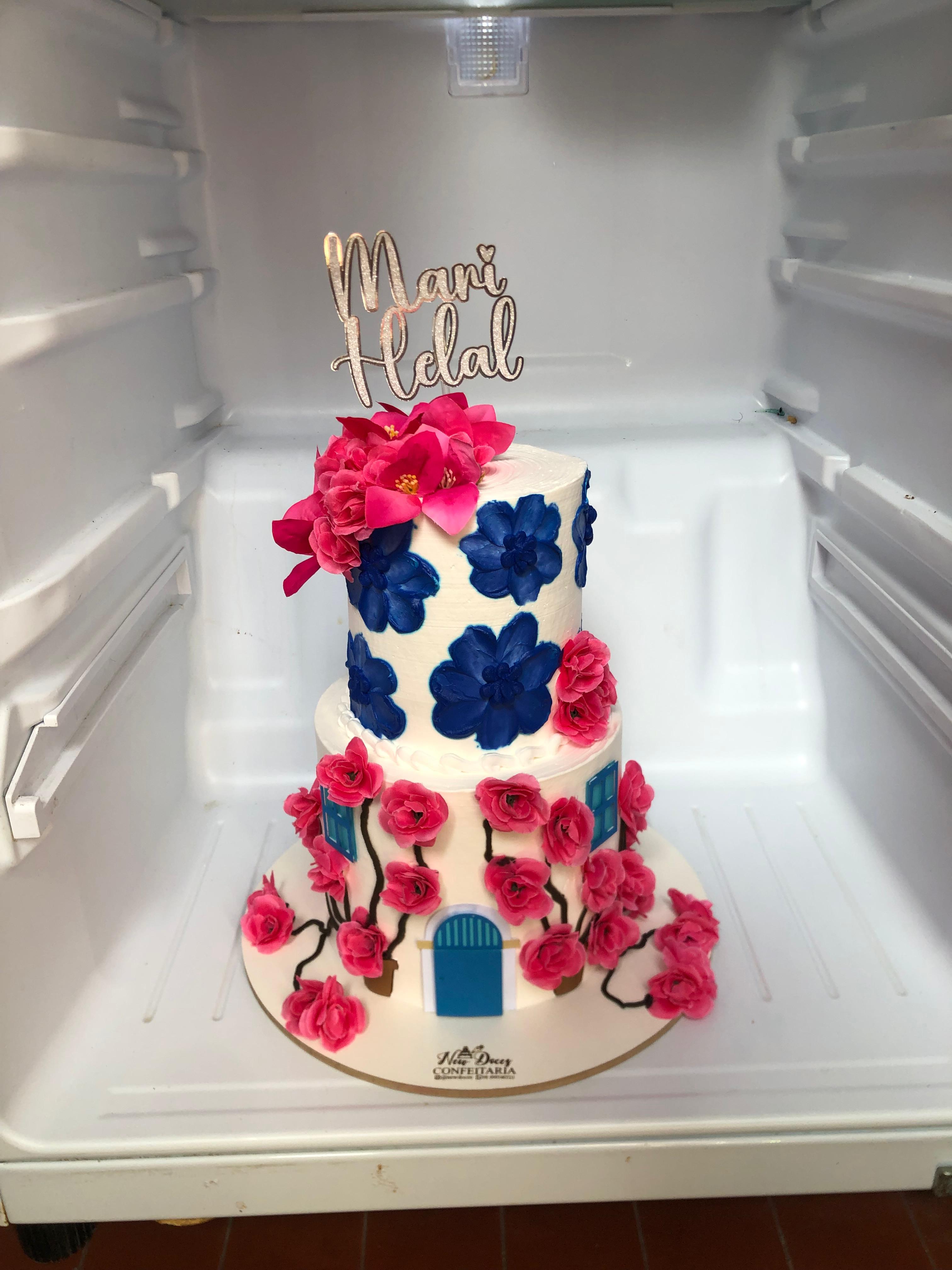 Bolo branco alto com flores decorativas vermelhas e azuis