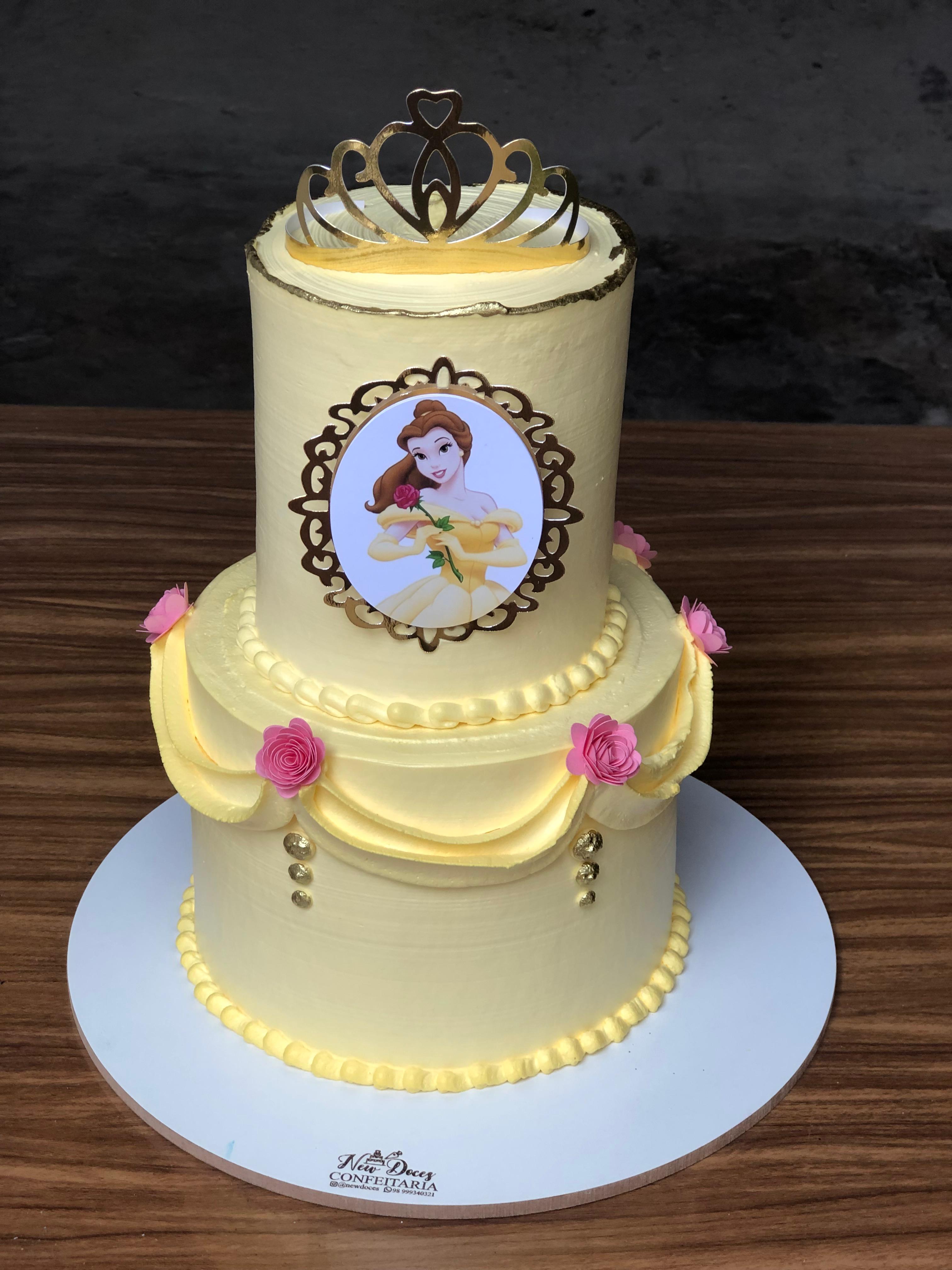 Bolo de dois andares amarelo e branco com coroa e detalhes decorativos