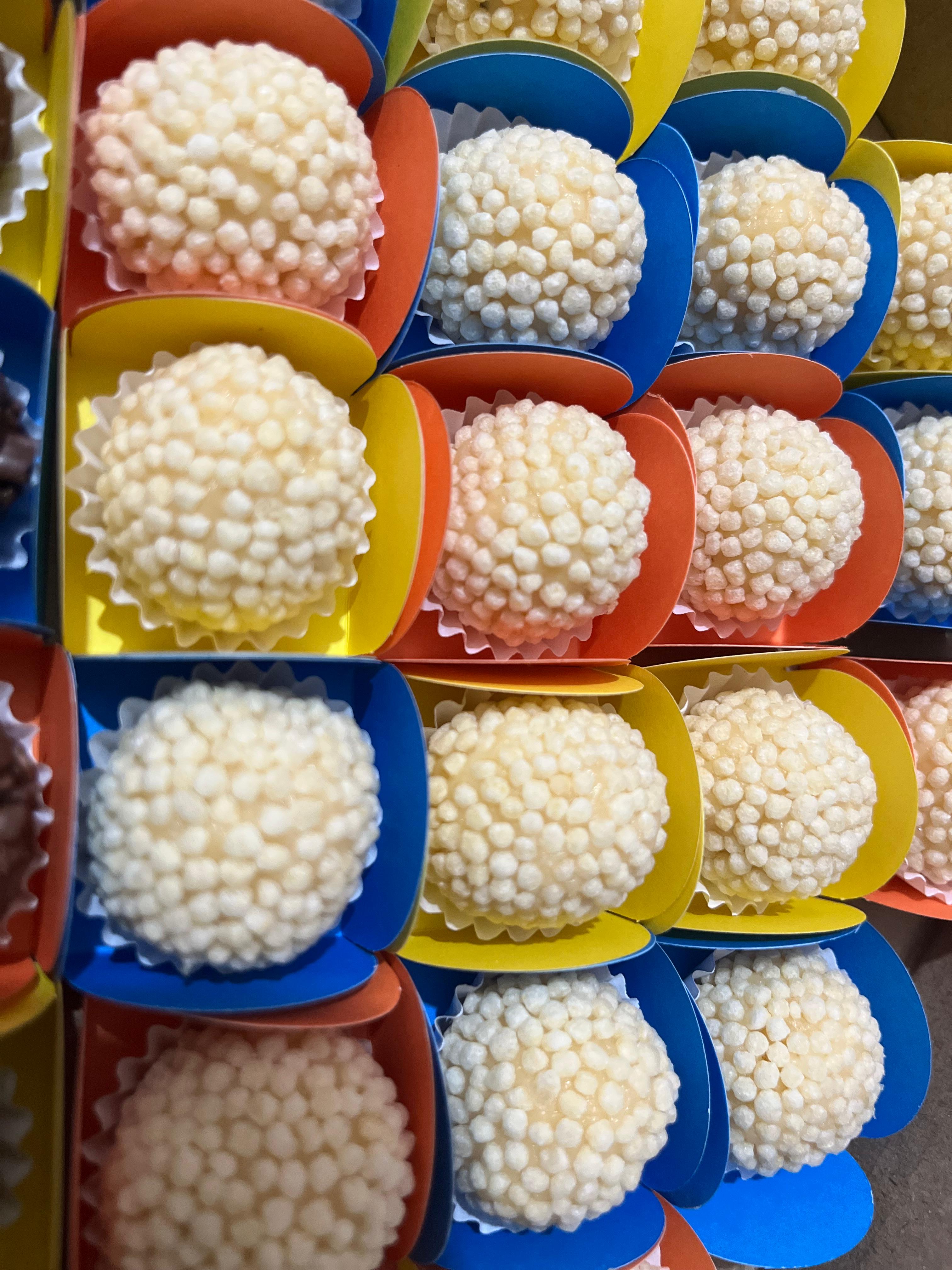 Docinhos claros com confeitos em forminhas azuis, amarelas e vermelhas