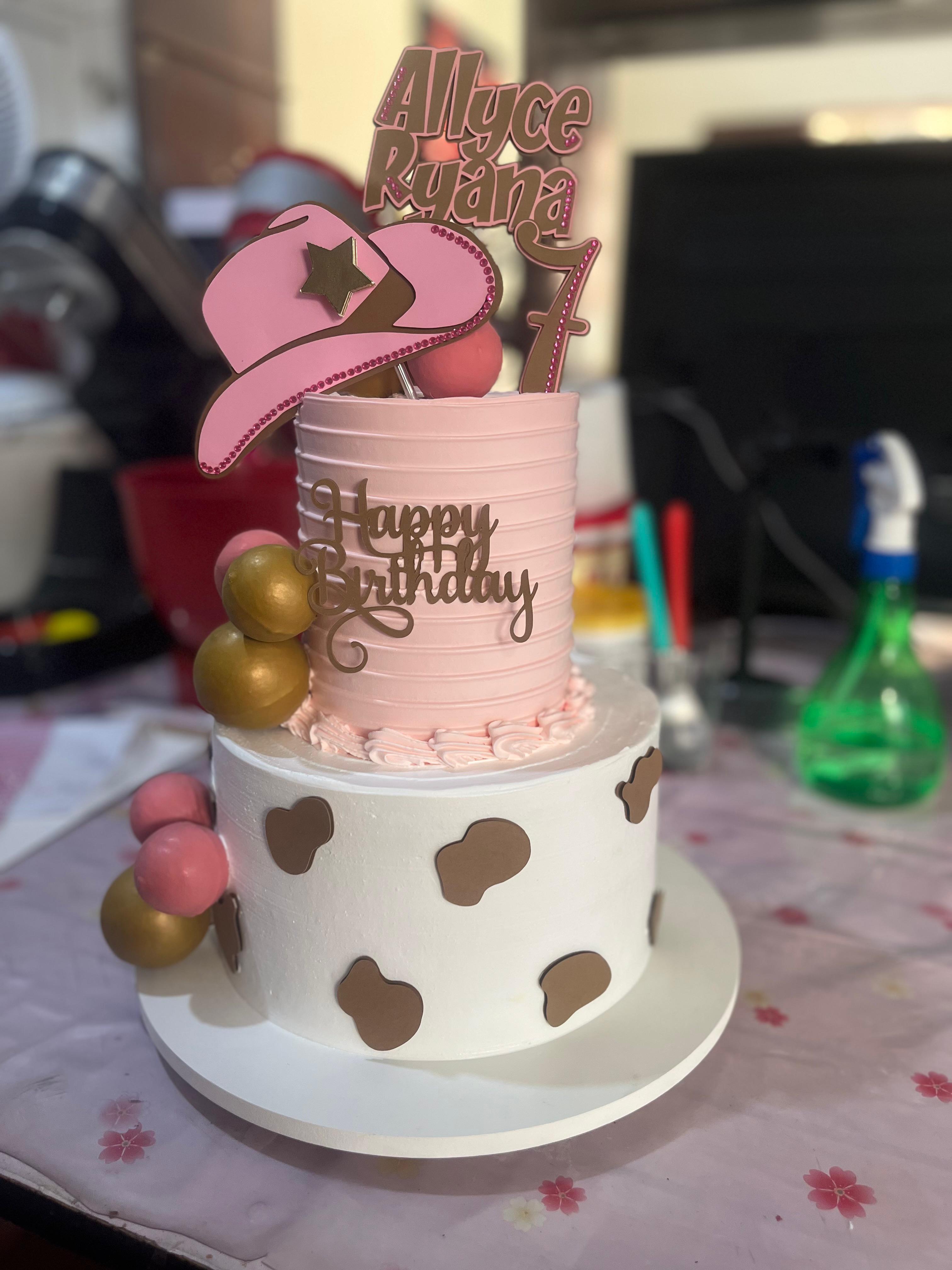 Bolo de dois andares branco e rosa com manchas marrons, chapéu e decoração temática