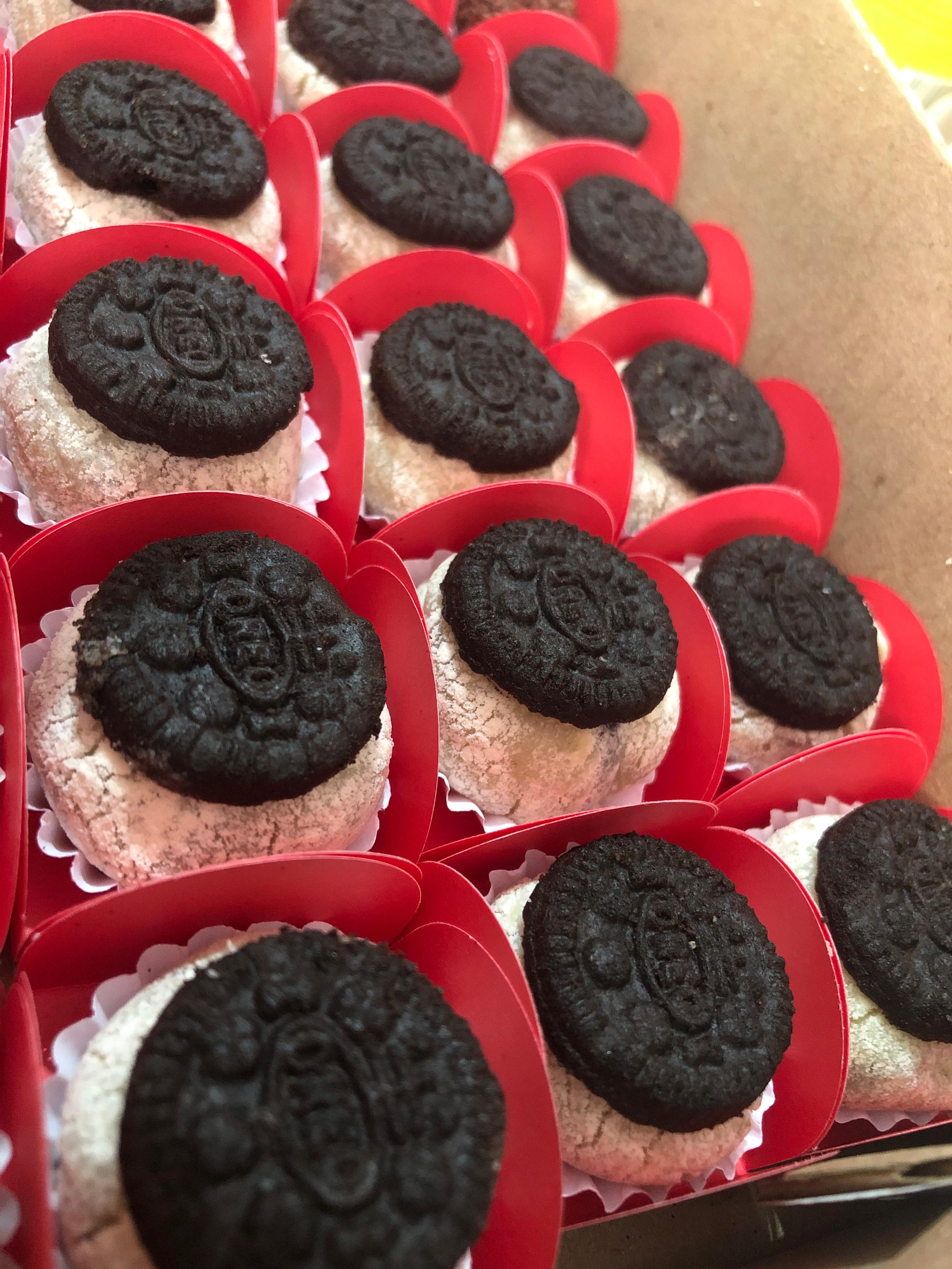 Docinhos claros com biscoitos escuros no topo em forminhas vermelhas