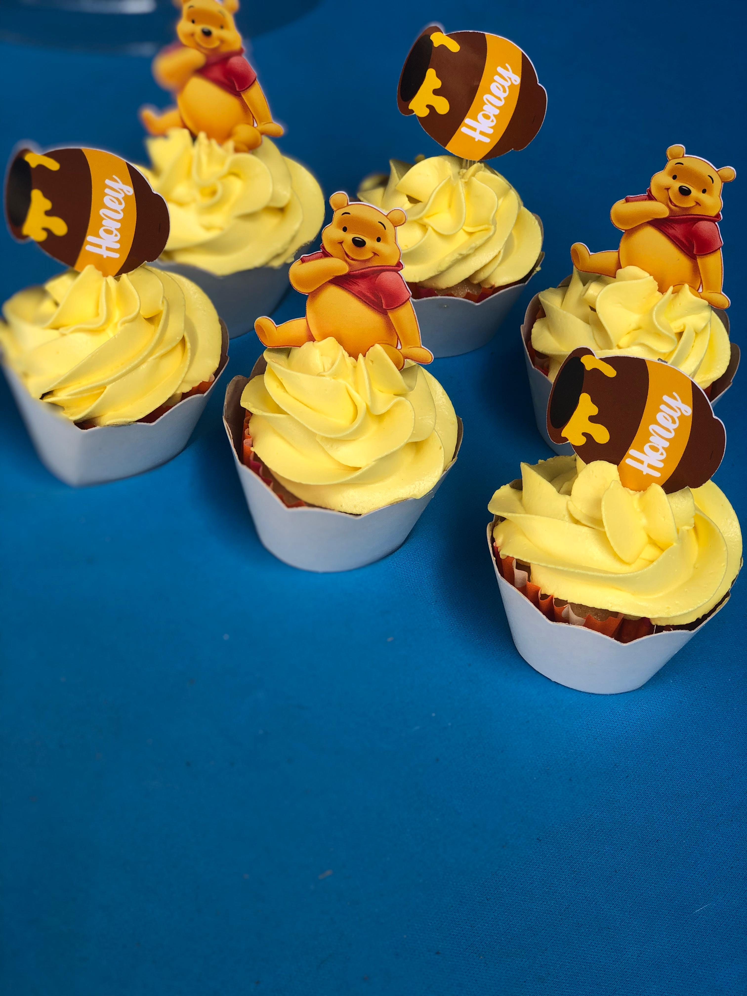 Cupcakes com cobertura amarela e toppers temáticos sobre mesa azul